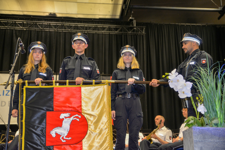 Auf der Bühne: zwei Polizeikommissaranwärterinnen und ein Polizeikommissaranwärter schwören ihren Eid.